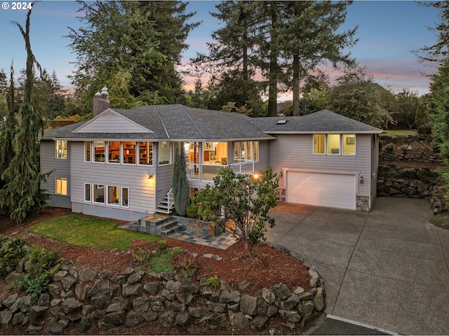 view of front of property with stairway, roof with shingles, an attached garage, a chimney, and concrete driveway