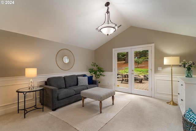 living room featuring a wainscoted wall, lofted ceiling, french doors, and light colored carpet