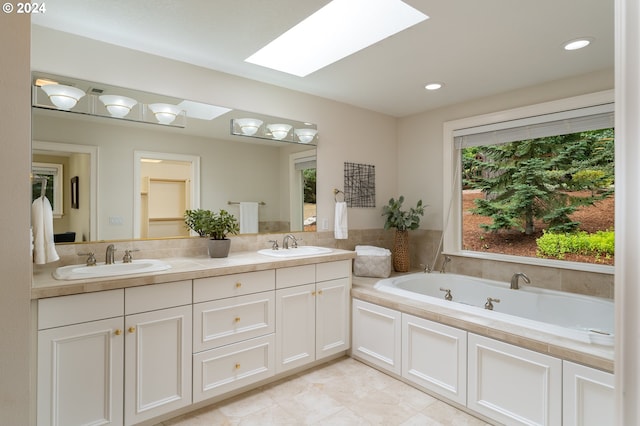 bathroom with double vanity, a skylight, a bath, and a sink