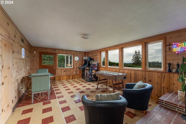 interior space featuring tile patterned floors, wooden walls, a wealth of natural light, and a textured ceiling