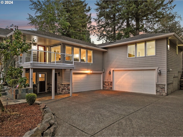 view of front of property featuring concrete driveway, a balcony, a garage, and stone siding