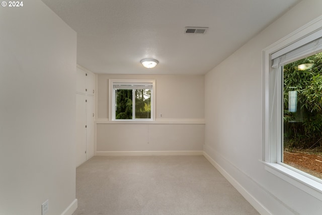 empty room featuring light colored carpet, visible vents, and baseboards