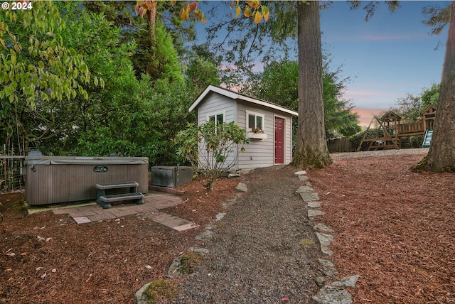 yard at dusk with an outbuilding and a hot tub