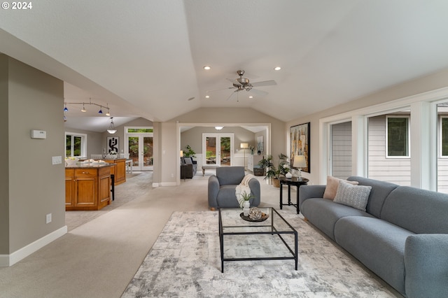 living area with light carpet, french doors, baseboards, and vaulted ceiling