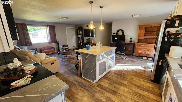 kitchen with white cabinetry, a center island, hanging light fixtures, and hardwood / wood-style flooring