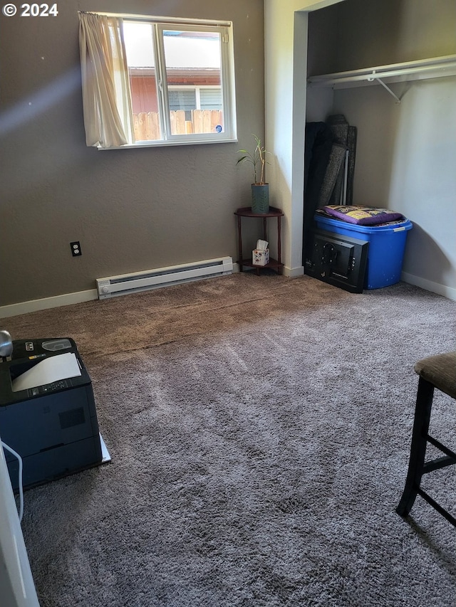 bedroom with dark colored carpet, a closet, and a baseboard heating unit