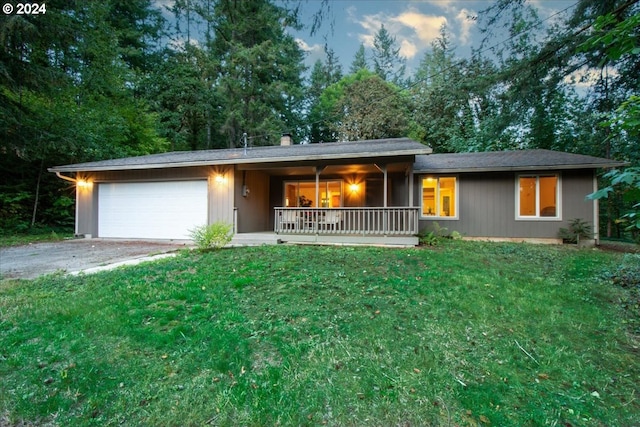 ranch-style house featuring a garage, a porch, and a yard