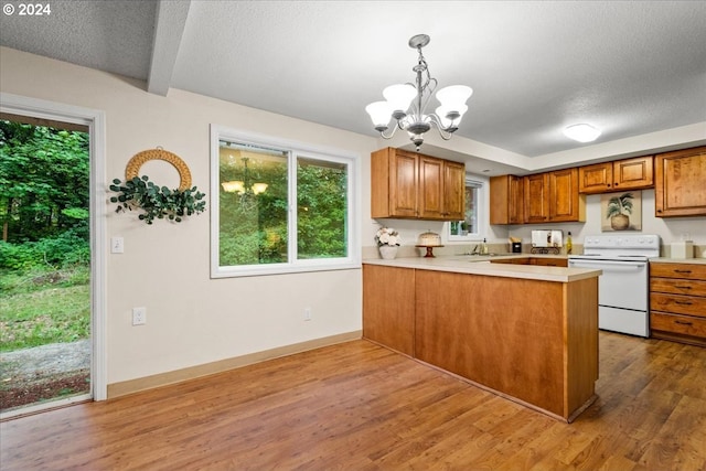 kitchen with white electric range oven, kitchen peninsula, decorative light fixtures, hardwood / wood-style flooring, and an inviting chandelier