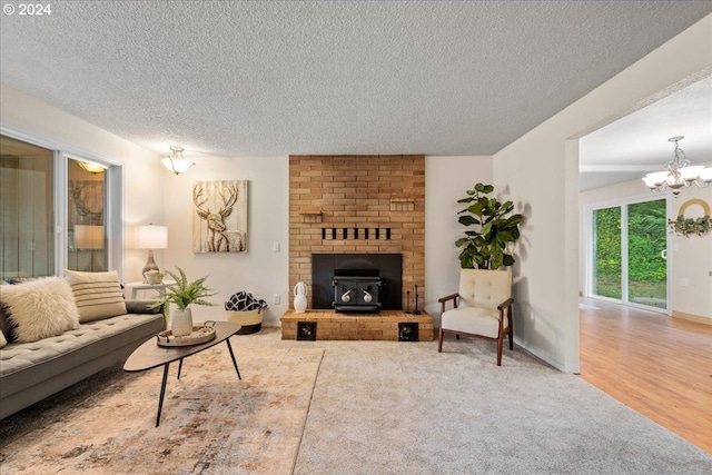 living room with a brick fireplace, a textured ceiling, a chandelier, and wood-type flooring