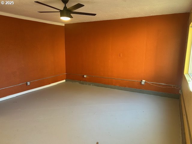 empty room featuring ceiling fan and concrete floors