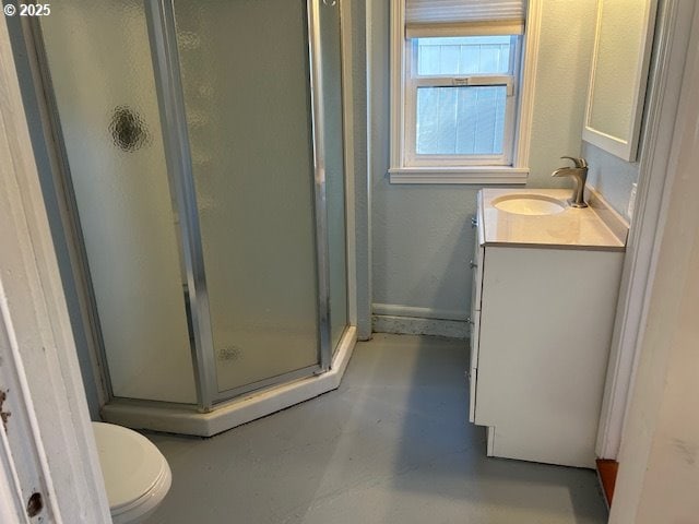 bathroom with concrete floors, vanity, a shower with shower door, and toilet