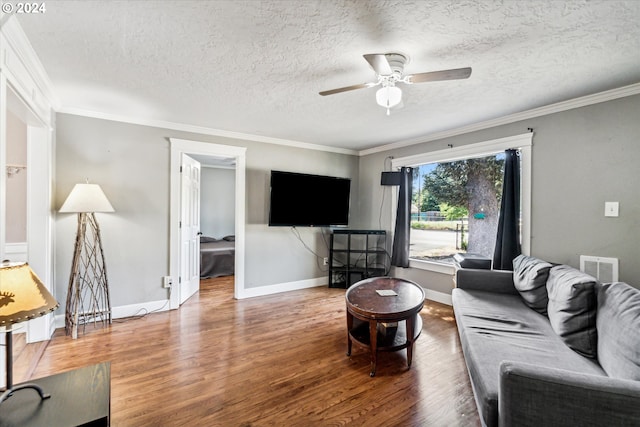 living room with hardwood / wood-style flooring, ceiling fan, a textured ceiling, and ornamental molding