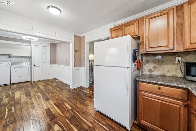 kitchen featuring dark hardwood / wood-style floors, white fridge, decorative backsplash, washer and clothes dryer, and ornamental molding