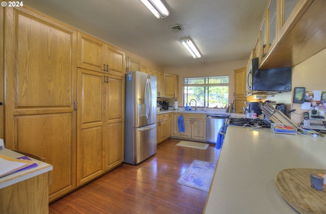 kitchen featuring stainless steel appliances, light brown cabinetry, dark hardwood / wood-style floors, and sink