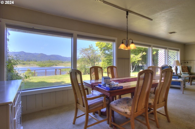 carpeted dining area featuring a notable chandelier and a water and mountain view