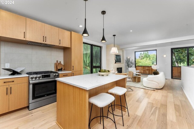 kitchen with plenty of natural light, light hardwood / wood-style flooring, light brown cabinets, gas range, and decorative light fixtures