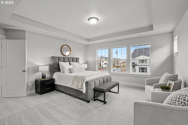 bedroom featuring light carpet and a raised ceiling