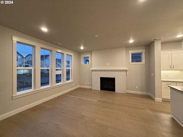 unfurnished living room with a fireplace and light wood-type flooring