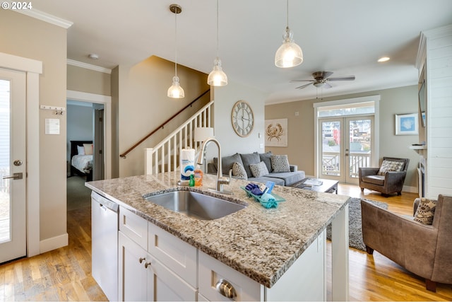 kitchen featuring sink, a center island with sink, white cabinetry, dishwasher, and light hardwood / wood-style floors