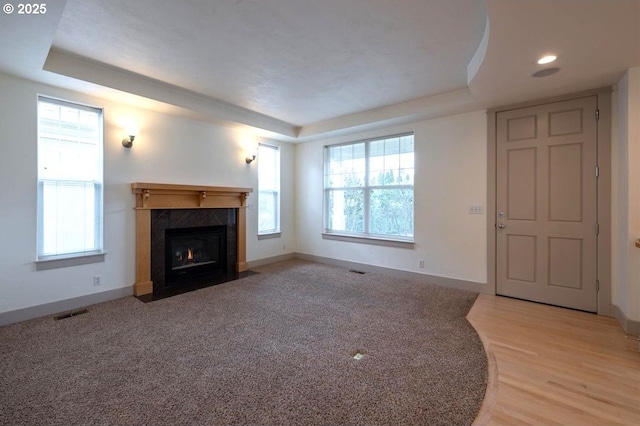 unfurnished living room featuring baseboards, visible vents, a tray ceiling, and a tiled fireplace