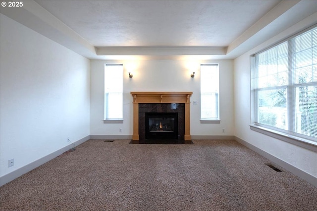 unfurnished living room featuring carpet, a tile fireplace, visible vents, and baseboards