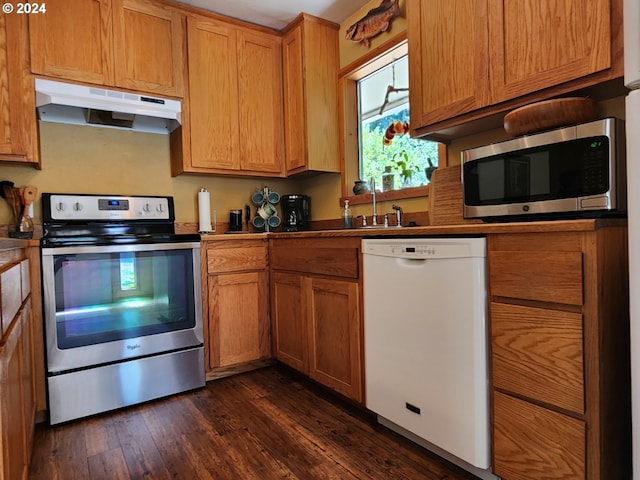 kitchen with dark wood-style floors, brown cabinets, appliances with stainless steel finishes, a sink, and under cabinet range hood