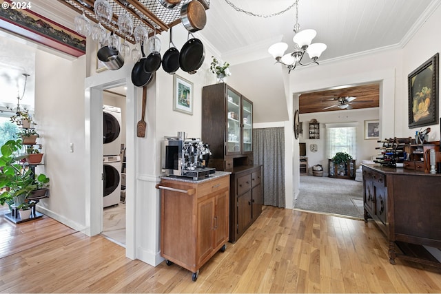 kitchen featuring ornamental molding, stacked washer and clothes dryer, ceiling fan with notable chandelier, and light hardwood / wood-style flooring