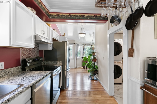 kitchen with pendant lighting, appliances with stainless steel finishes, stacked washer and clothes dryer, white cabinets, and decorative backsplash