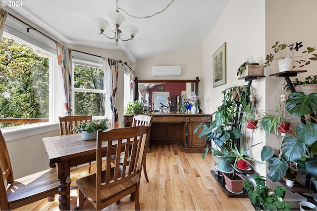 dining area with an inviting chandelier, an AC wall unit, lofted ceiling, and light wood-type flooring