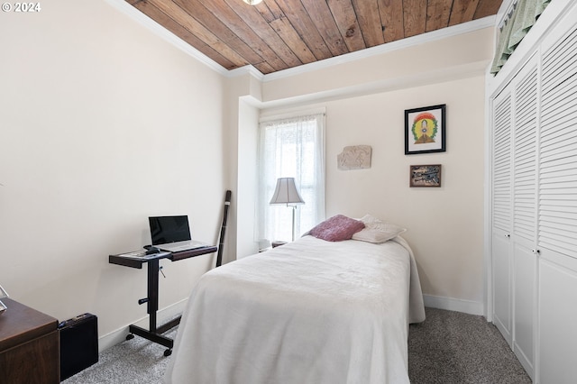 carpeted bedroom with ornamental molding, wood ceiling, and a closet