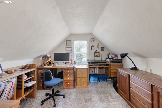 office area with vaulted ceiling, light colored carpet, and a textured ceiling