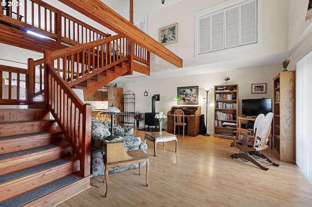 living room featuring a towering ceiling, light hardwood / wood-style floors, and a wood stove