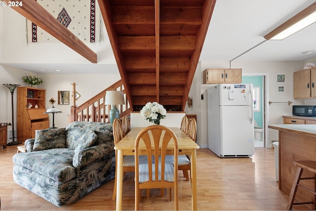 dining area with beamed ceiling, wood ceiling, and light wood-type flooring