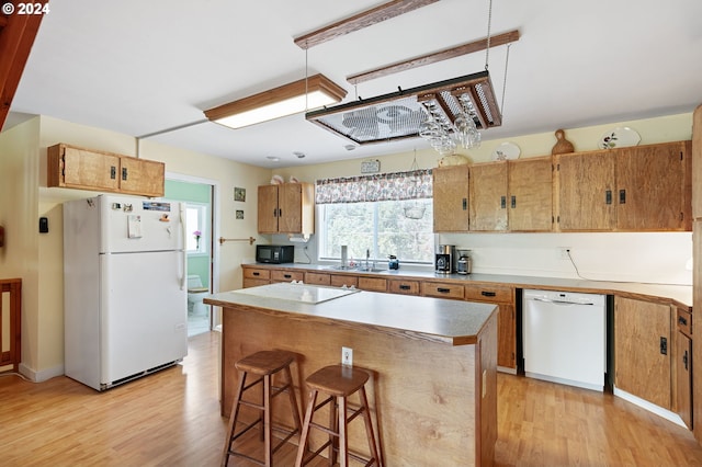 kitchen featuring white appliances, light wood-type flooring, a center island, and a kitchen bar