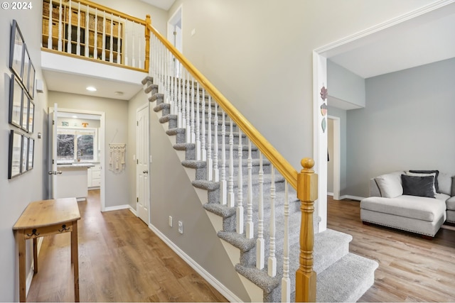 stairs featuring hardwood / wood-style floors and a high ceiling