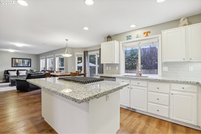 kitchen featuring a center island, white cabinets, sink, hanging light fixtures, and tasteful backsplash