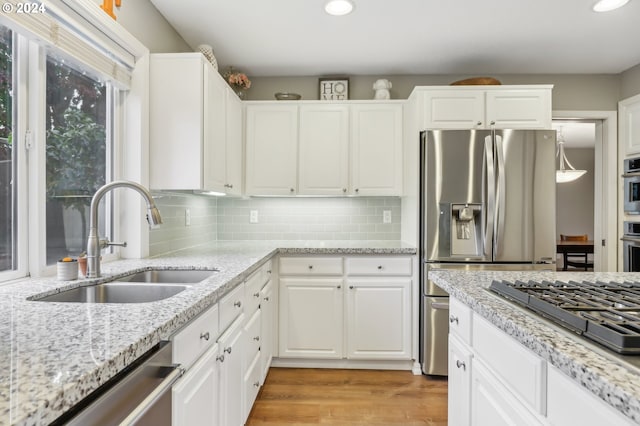 kitchen featuring sink, decorative backsplash, light stone counters, white cabinetry, and stainless steel appliances