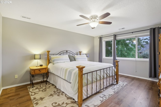 bedroom with a textured ceiling, ceiling fan, and dark wood-type flooring