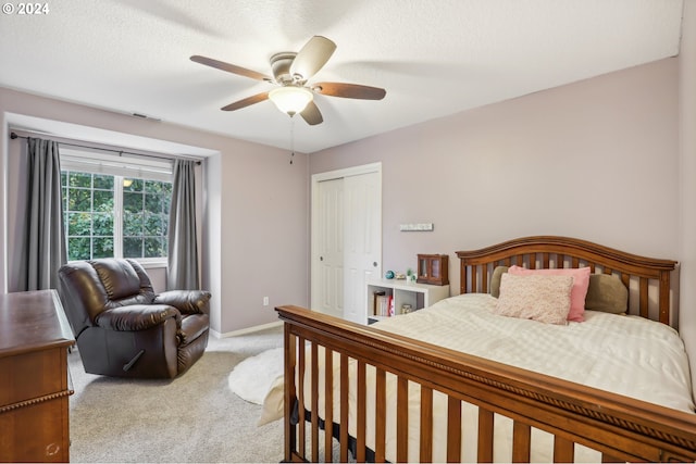 carpeted bedroom with ceiling fan, a textured ceiling, and a closet