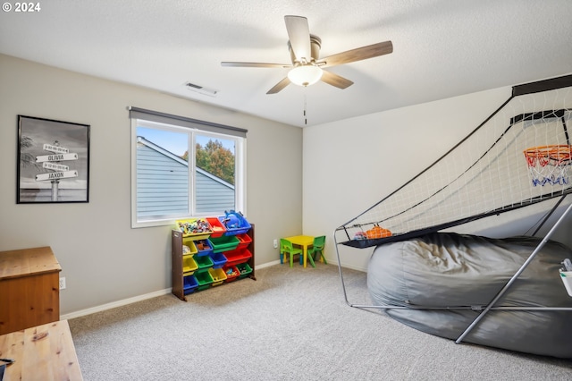 playroom featuring ceiling fan, carpet, and a textured ceiling