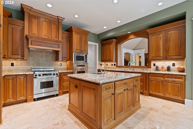 kitchen with appliances with stainless steel finishes, backsplash, a kitchen island with sink, and sink