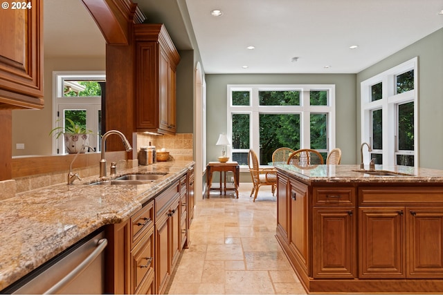 kitchen featuring dishwasher, light stone counters, sink, and tasteful backsplash