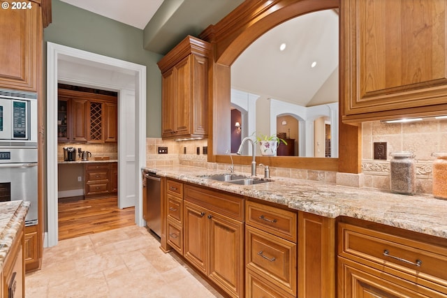 12320 NW Sargent Ln, Portland, OR 97231 - kitchen with a sink, stainless steel appliances, arched walkways, brown cabinets, and light stone counters