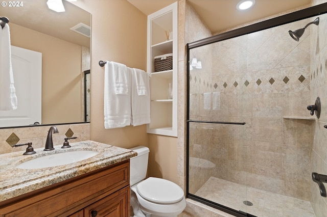 bathroom with vanity, toilet, a shower with door, and tasteful backsplash