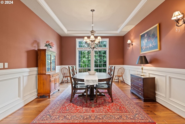 dining area featuring hardwood / wood-style floors, a tray ceiling, and a notable chandelier