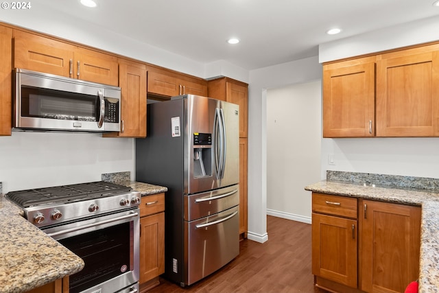 kitchen featuring light stone countertops, appliances with stainless steel finishes, and dark hardwood / wood-style floors