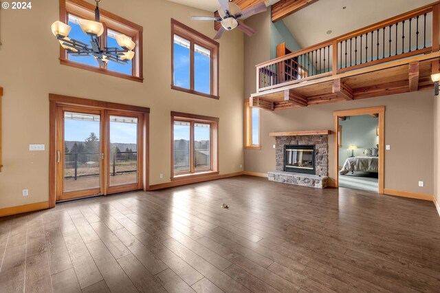 unfurnished living room featuring beam ceiling, high vaulted ceiling, hardwood / wood-style floors, a fireplace, and ceiling fan with notable chandelier