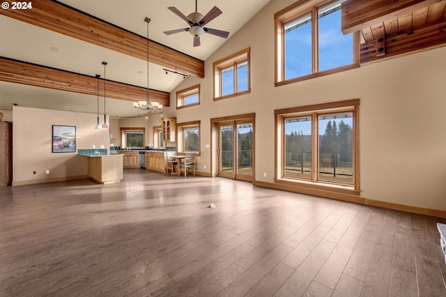 unfurnished living room with ceiling fan with notable chandelier, beam ceiling, high vaulted ceiling, and light hardwood / wood-style flooring