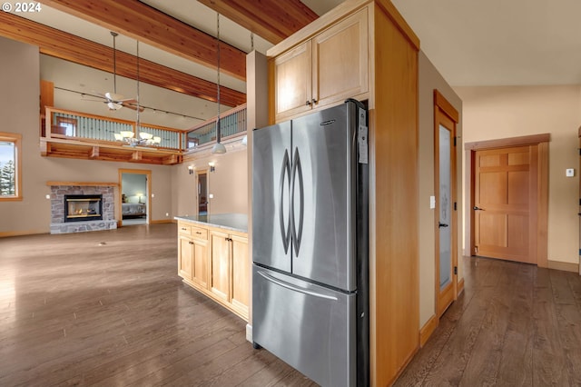 kitchen with a fireplace, light brown cabinetry, stainless steel refrigerator, and dark wood-type flooring