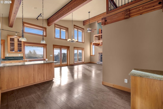 kitchen with dark stone counters, high vaulted ceiling, pendant lighting, and dark hardwood / wood-style floors